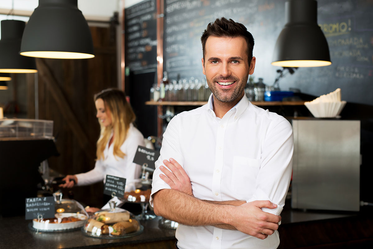 Restaurant worker smiling and standing with arms crossed.
